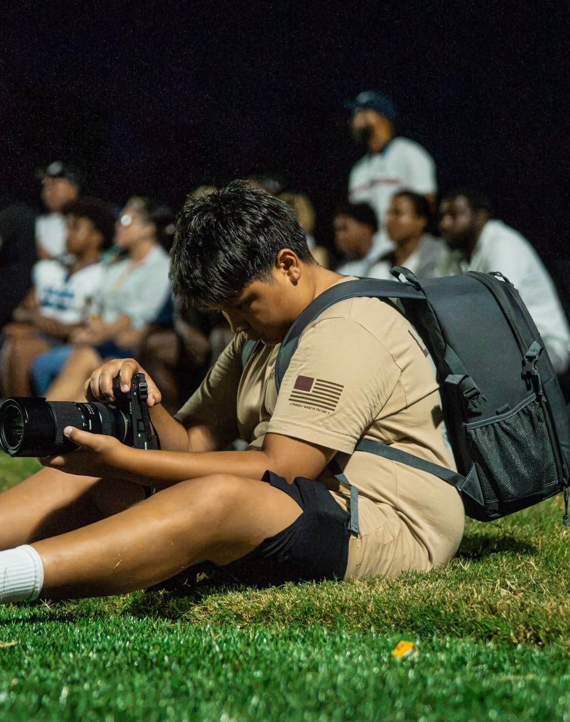 Matteo de Moya on the sideline at night, reviewing photos on his camera